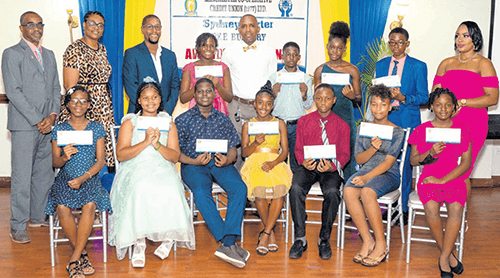 Recipients of the Manchester Co-operative Credit Union scholarship and bursary awards smiling at the awards banquet as credit union staff look on.